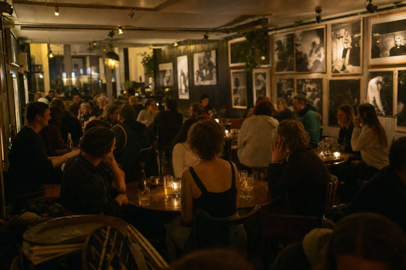 Masalarında mumlar yanan ve duvarları fotoğraflarla kaplı kalabalık bir bar