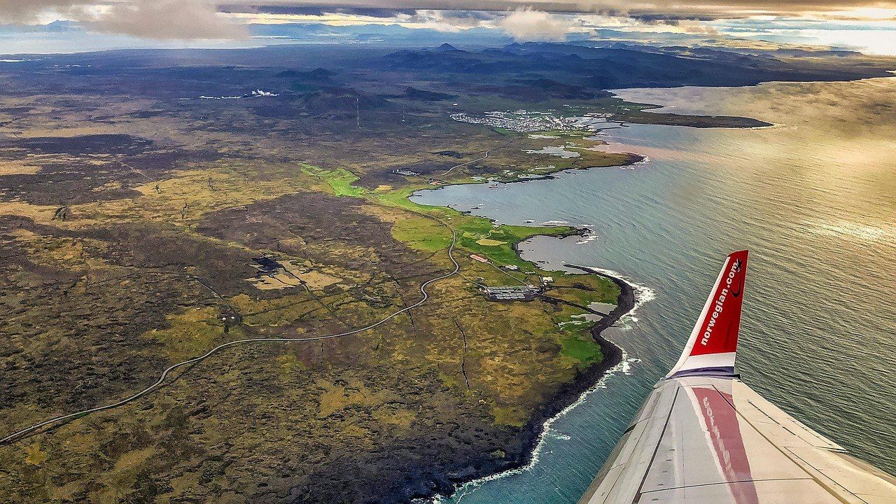 An aircraft wing over the Icelandic coast, seen from a passenger window
